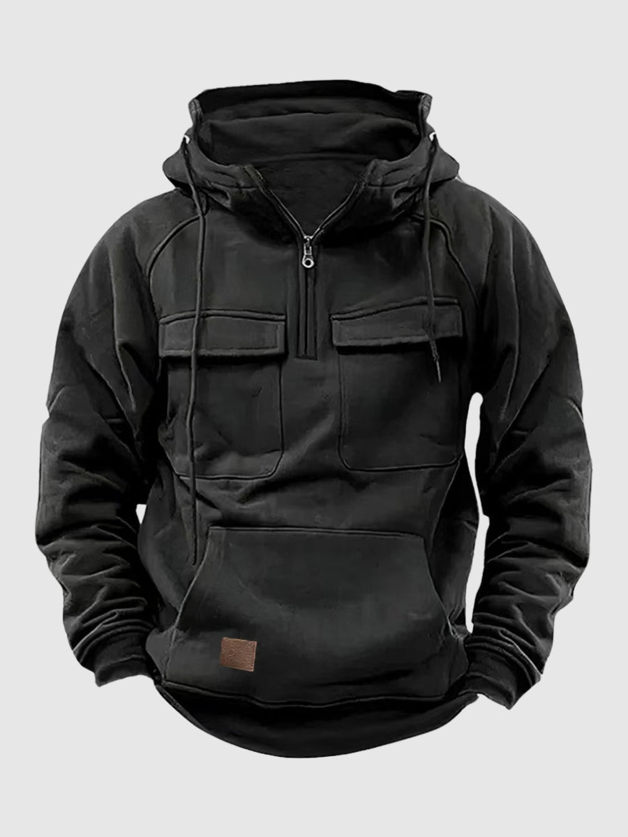 Black tactical pullover hoodie with a half-zip stand collar, adjustable hood, flap chest pockets, and kangaroo pocket displayed on a white background.