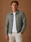 Man wearing a gray leather jacket with a shirt collar, zip-front closure, and minimalist design over a white T-shirt.