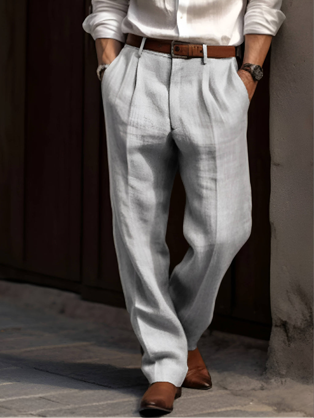 Man wearing white linen trousers featuring a relaxed straight-leg fit, pleated front, and brown leather belt.