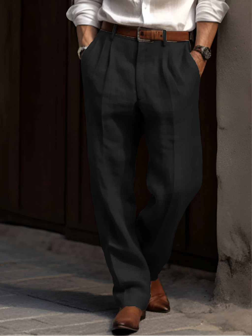 Man wearing black linen trousers with a relaxed straight-leg fit, pleated front, and brown leather belt.