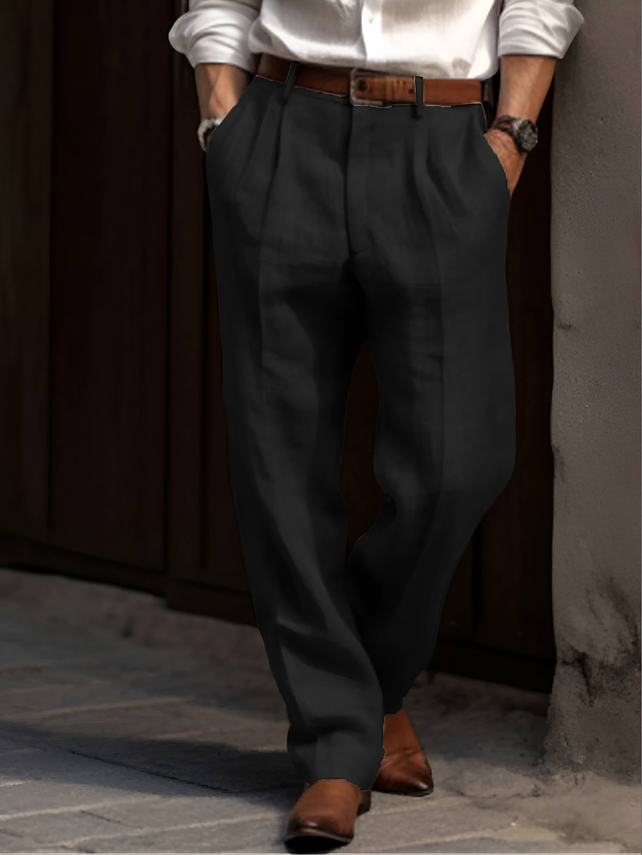 Man wearing black linen trousers with a relaxed straight-leg fit, pleated front, and brown leather belt.