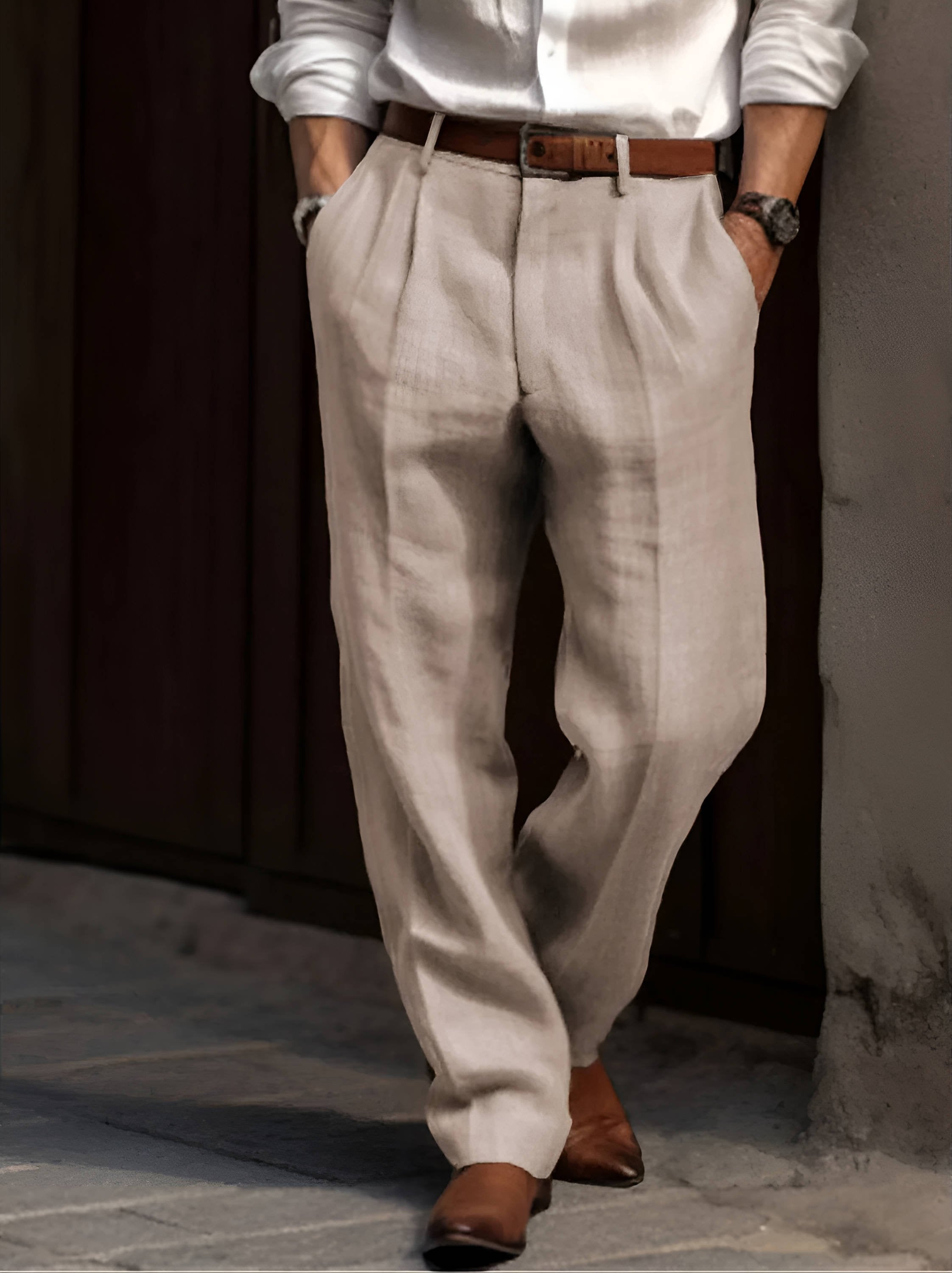 Man wearing beige linen trousers with a relaxed straight-leg fit, pleated front, belt loops, and side pockets.