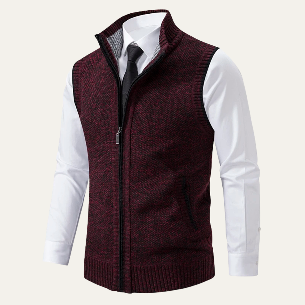 Men's burgundy knit zip-up sweater vest featuring a stand collar, sleeveless design, ribbed hem, and zip pockets worn over a white dress shirt.