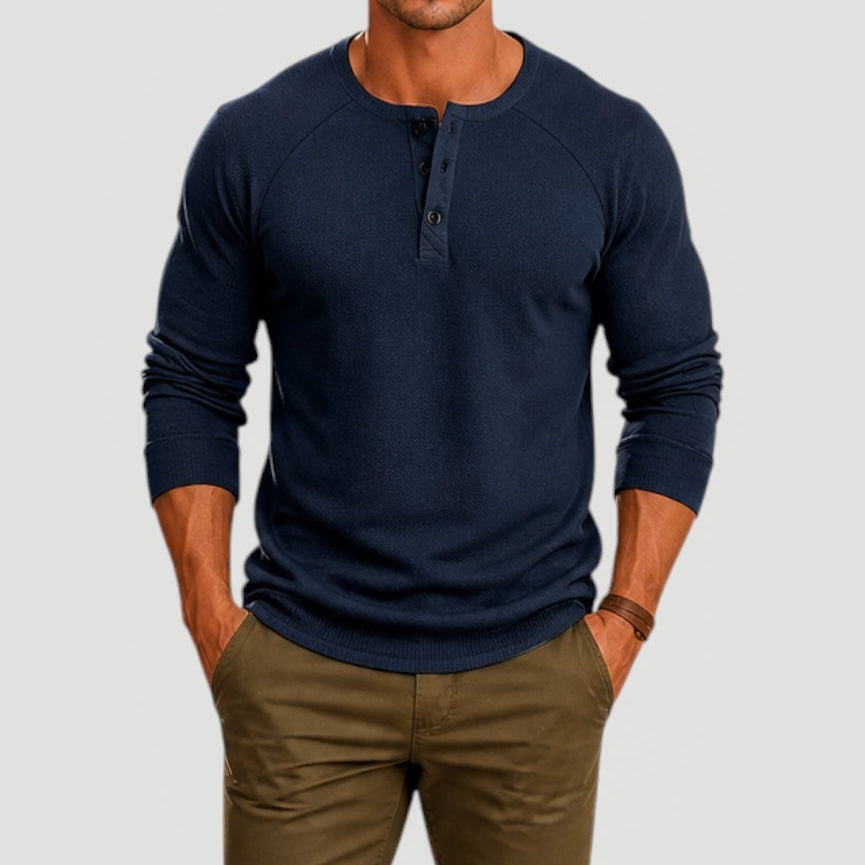 Man wearing a navy long-sleeve Henley sweater with a three-button placket and textured knit fabric.