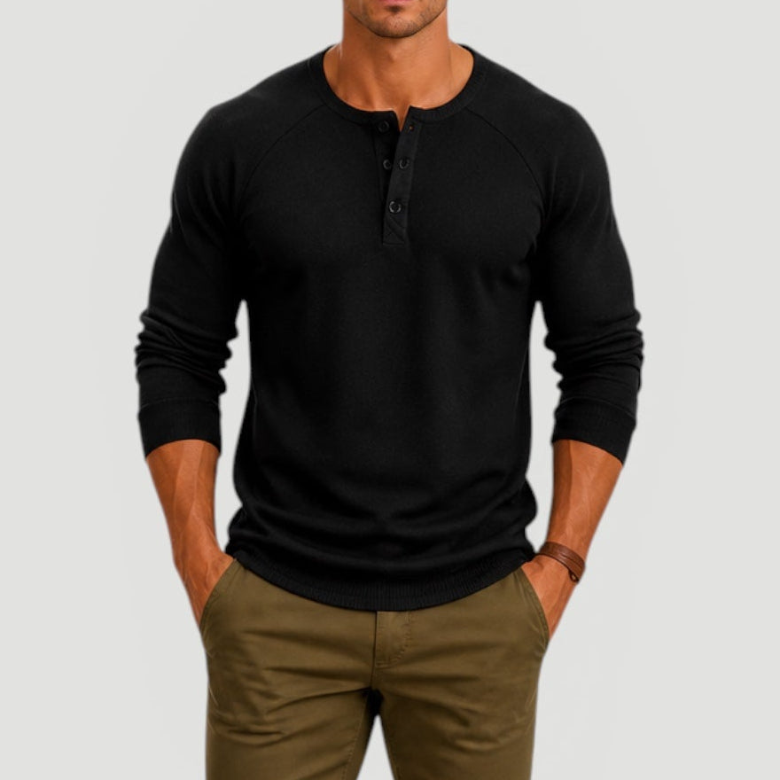 Man wearing a black long-sleeve Henley sweater featuring a three-button placket, ribbed cuffs, and a classic fit.