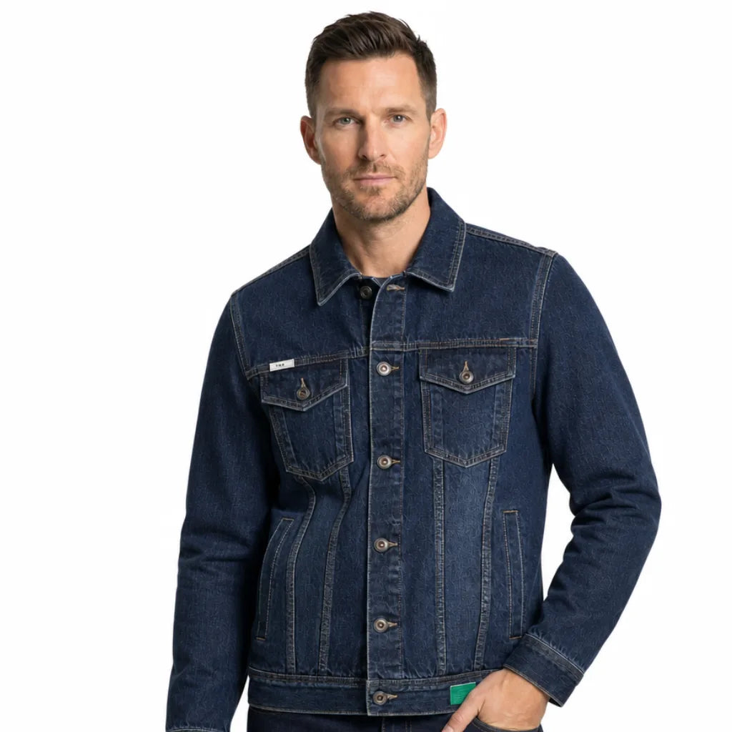Man wearing a dark wash denim jacket with a button-front closure, chest flap pockets, contrast stitching, and a classic trucker fit.