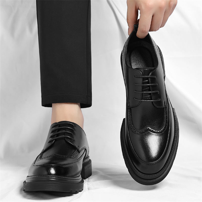 Man in black trousers wearing one black leather Julian brogue dress shoe while holding the matching shoe by hand