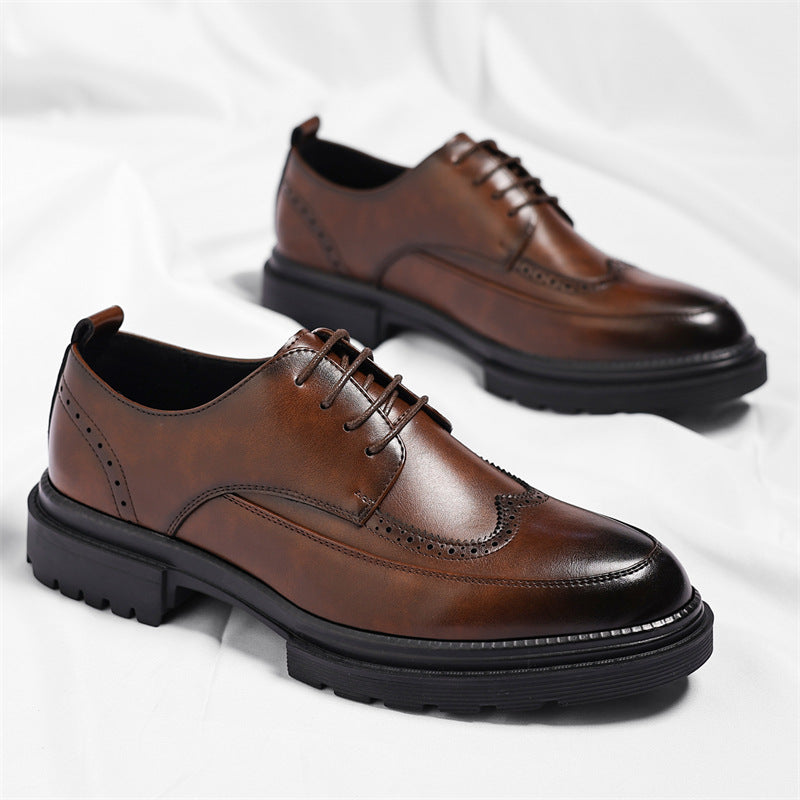 Pair of brown leather Julian brogue dress shoes with wingtip stitching, one propped on the other on a white fabric backdrop