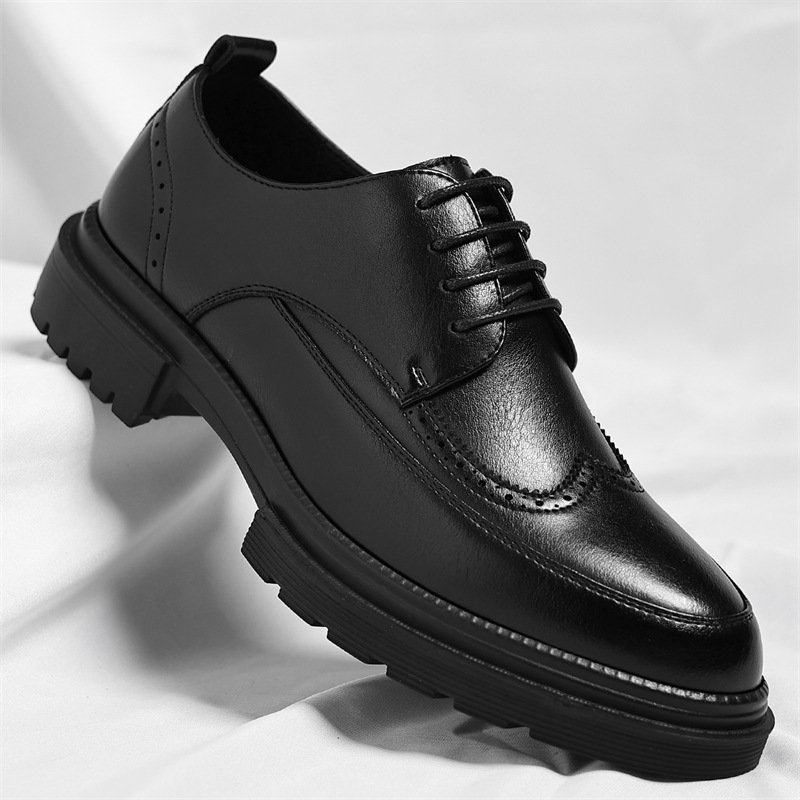 Single black leather Julian brogue dress shoe with wingtip stitching, tilted on a white fabric backdrop