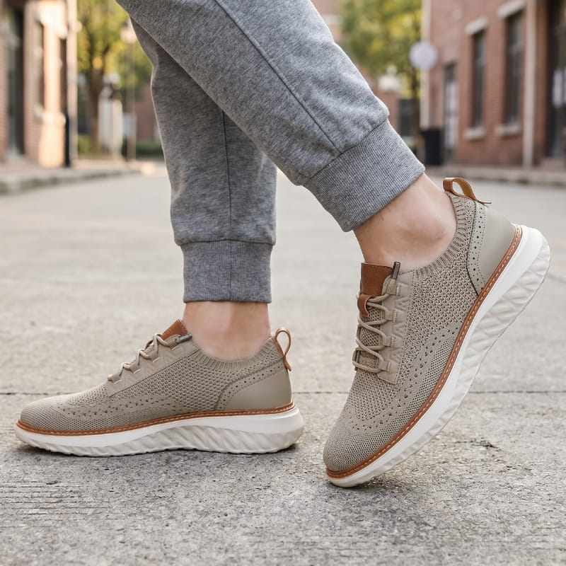 Person wearing khaki mesh sneakers with brown trim and gray joggers, walking on a city street