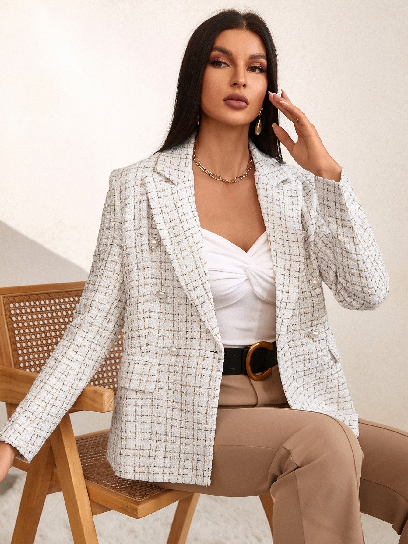 Woman wearing a beige and white tweed blazer with gold-tone buttons, notched lapels, and tailored fit over a white top and beige trousers.