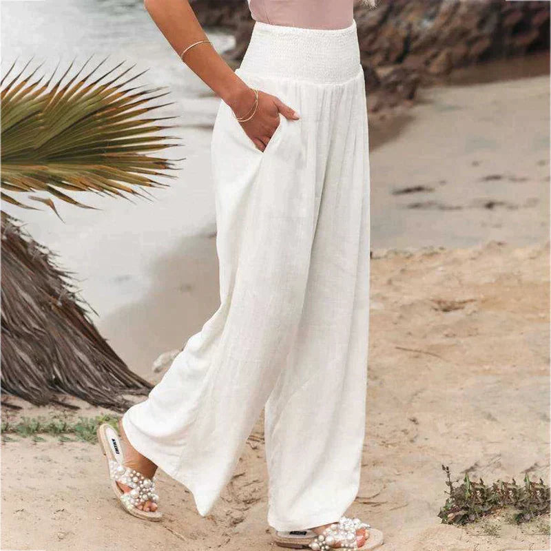 Side view of women's white high-waisted linen pants with a wide-leg silhouette and soft drape.