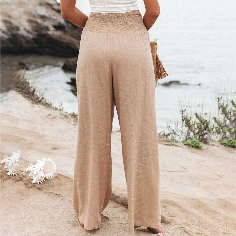 Back view of women's beige wide-leg linen pants with an elastic waistband and relaxed fit.