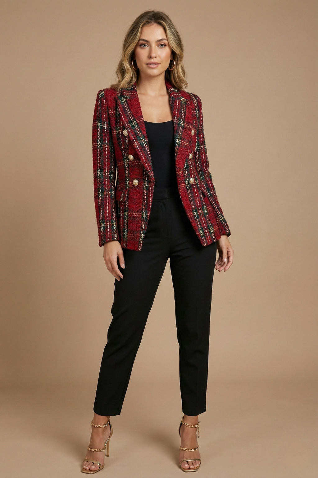 Woman wearing a red plaid tweed blazer with gold-tone buttons, notched lapels, and tailored fit over a black top and trousers.