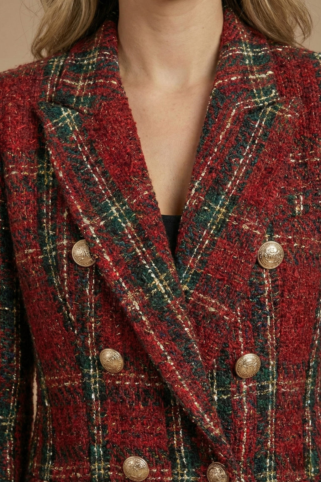 Close-up of a red plaid tweed blazer showing the textured fabric, notched lapels, and gold-tone buttons.