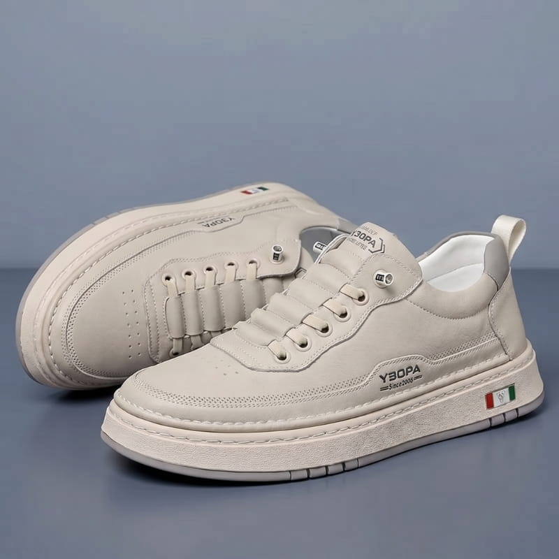Pair of beige leather chunky sneakers stacked at an angle on a blue-gray studio background