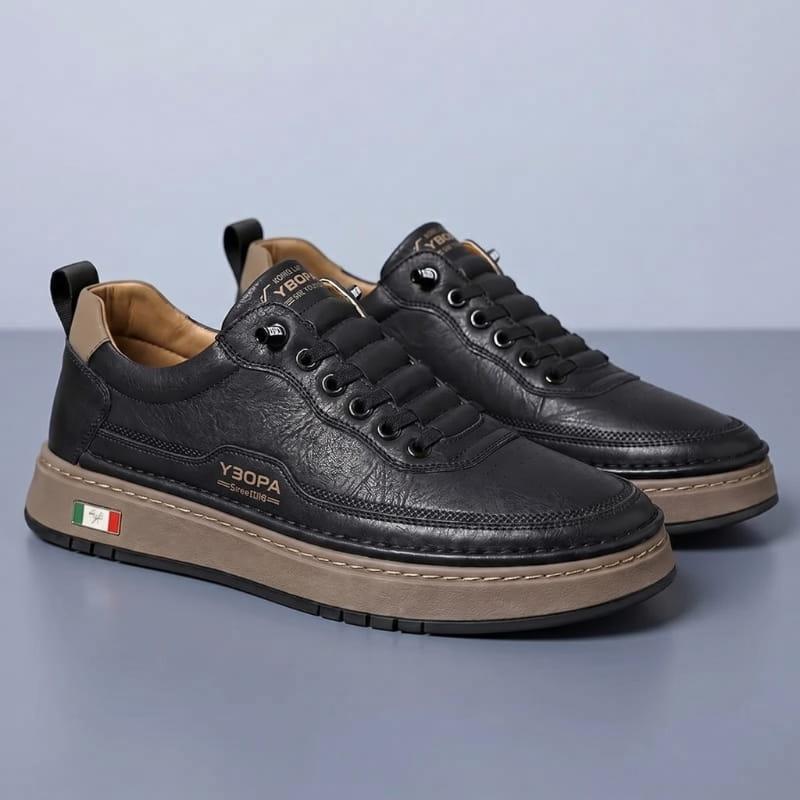 Pair of black leather chunky sneakers with tan soles facing forward on a gray studio background