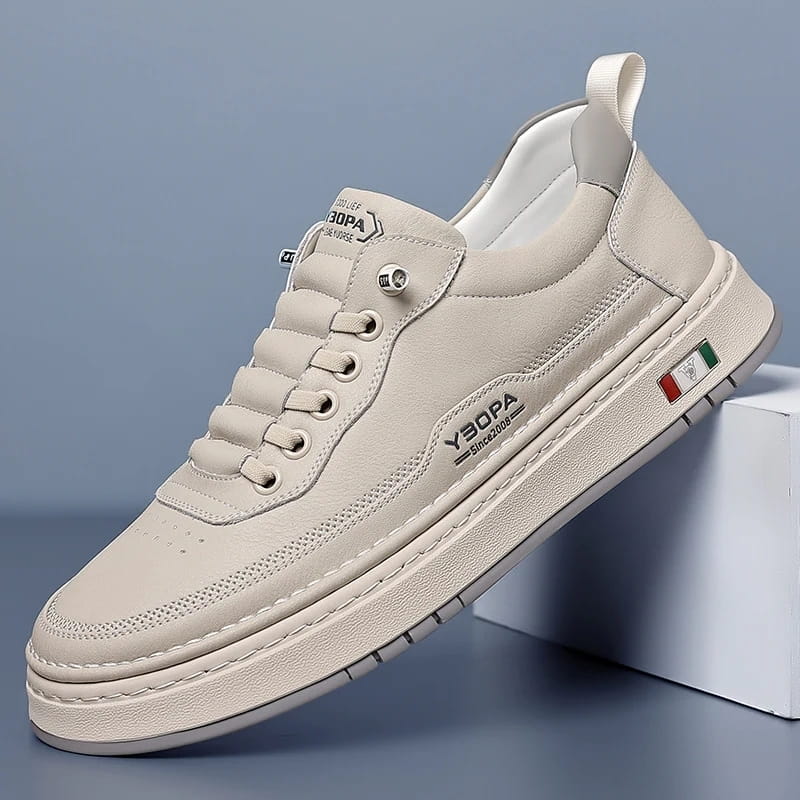 Beige leather chunky sneaker with white sole propped diagonally against a white block on a blue studio background