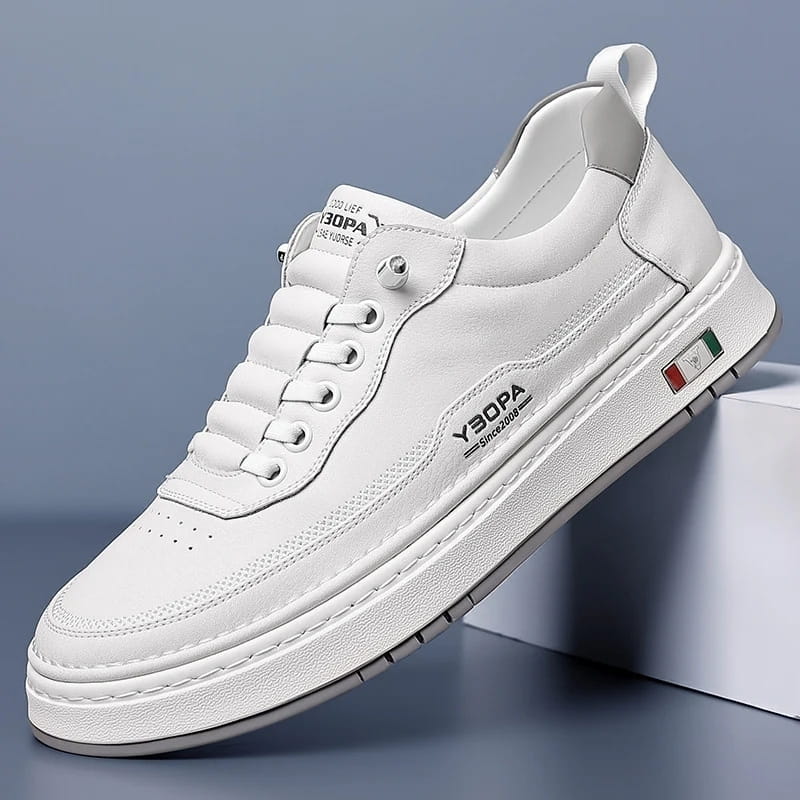 White leather chunky sneaker with textured sole propped diagonally against a white block on a blue studio background