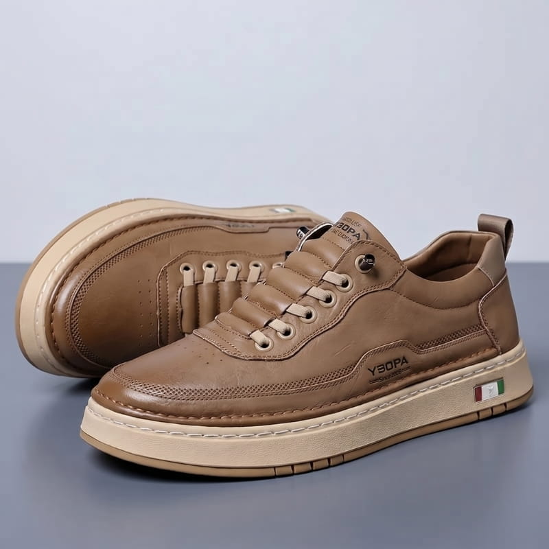 Pair of brown leather chunky sneakers with tan soles stacked at an angle on a gray studio background