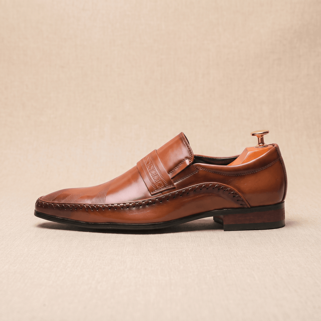 Single brown leather Leonardo loafer shown in side profile with wooden shoe tree on beige backdrop
