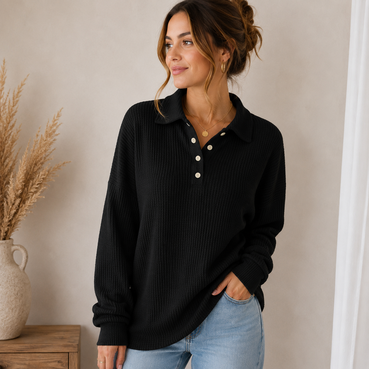 Woman wearing a black ribbed knit polo sweater with a collared button neckline, long sleeves, and a relaxed silhouette.