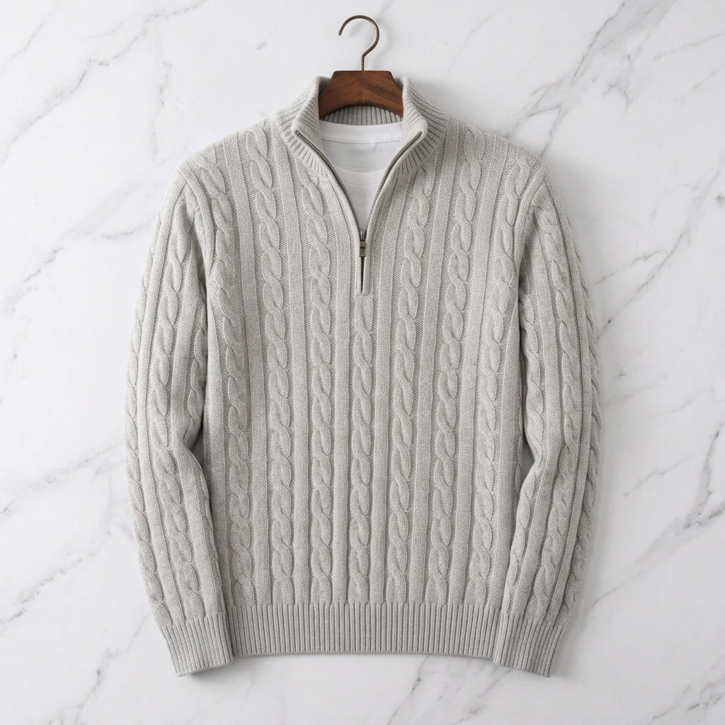 Light gray cable knit half-zip sweater with ribbed cuffs and stand collar displayed on a marble background.