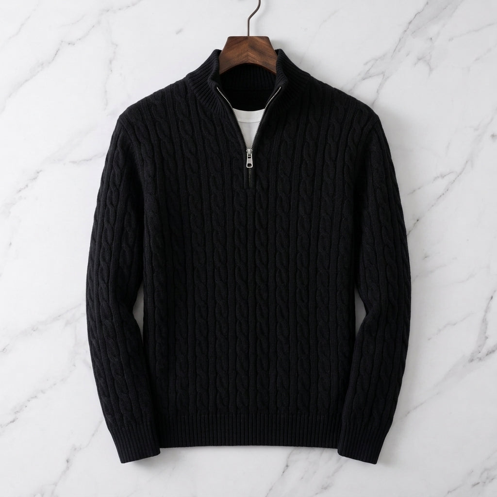 Black cable knit half-zip sweater with ribbed cuffs and stand collar displayed on a marble background.