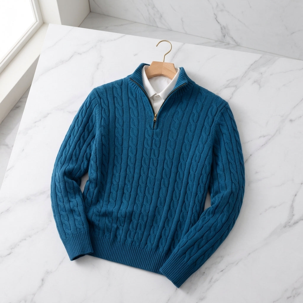 Blue cable knit half-zip sweater with ribbed cuffs and stand collar displayed on a white surface.