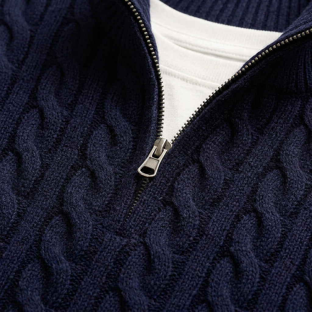 Close-up of a navy cable knit half-zip sweater showcasing the textured knit pattern, metal zipper, and stand collar.