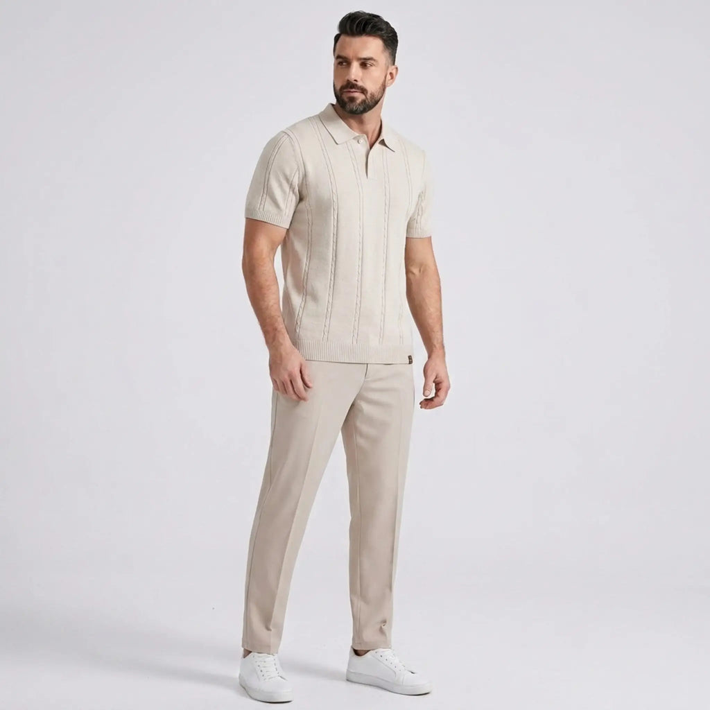 Man wearing a beige short-sleeve knit polo shirt with matching beige trousers in a full-body studio portrait.