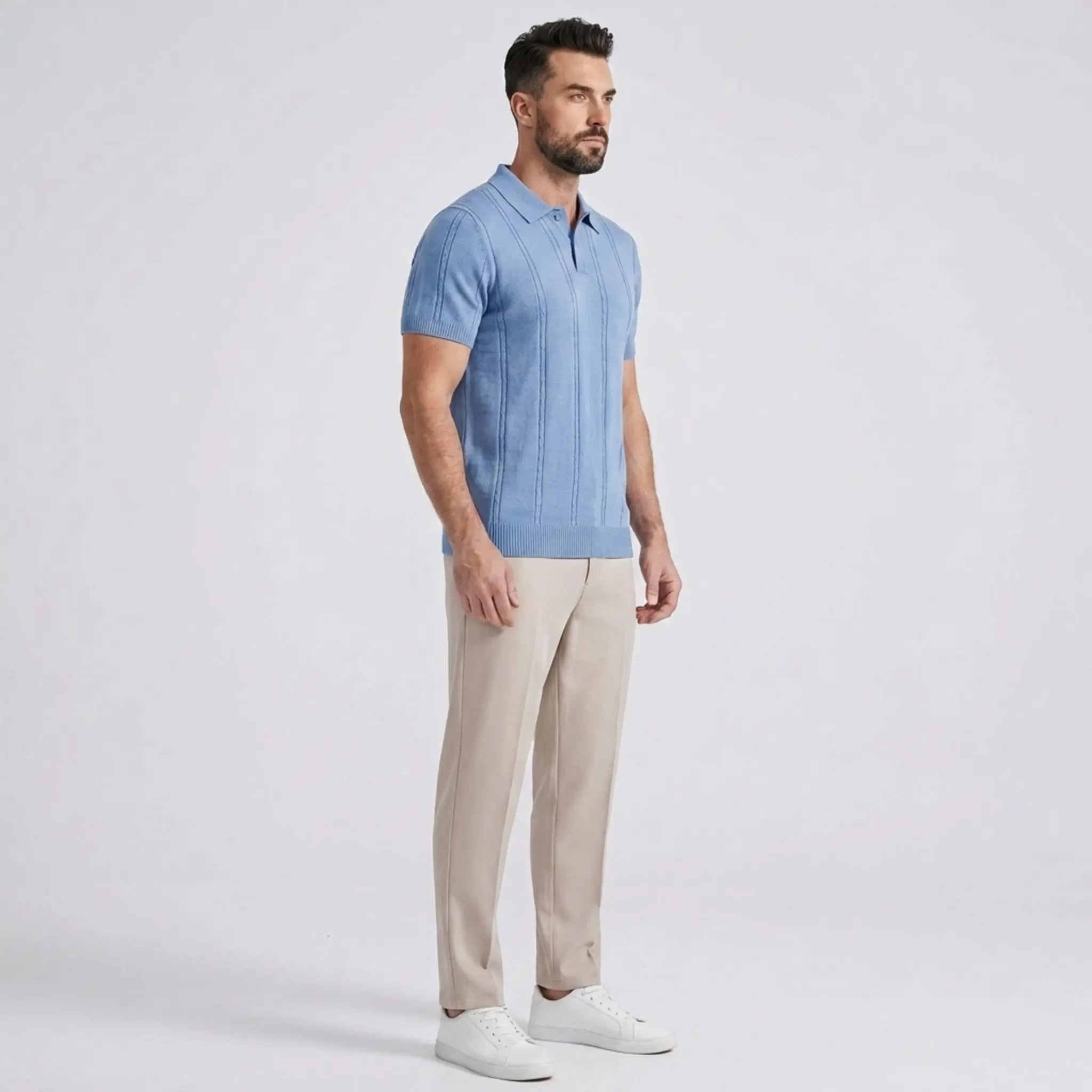 Side view of a man wearing a light blue knit polo shirt paired with beige trousers and white sneakers.