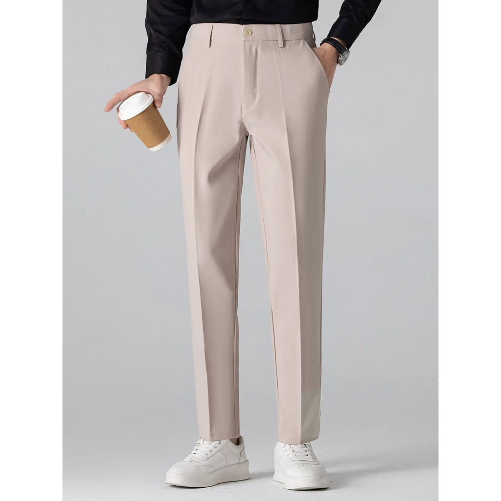 Man wearing beige tailored trousers paired with a black top while holding a coffee cup.
