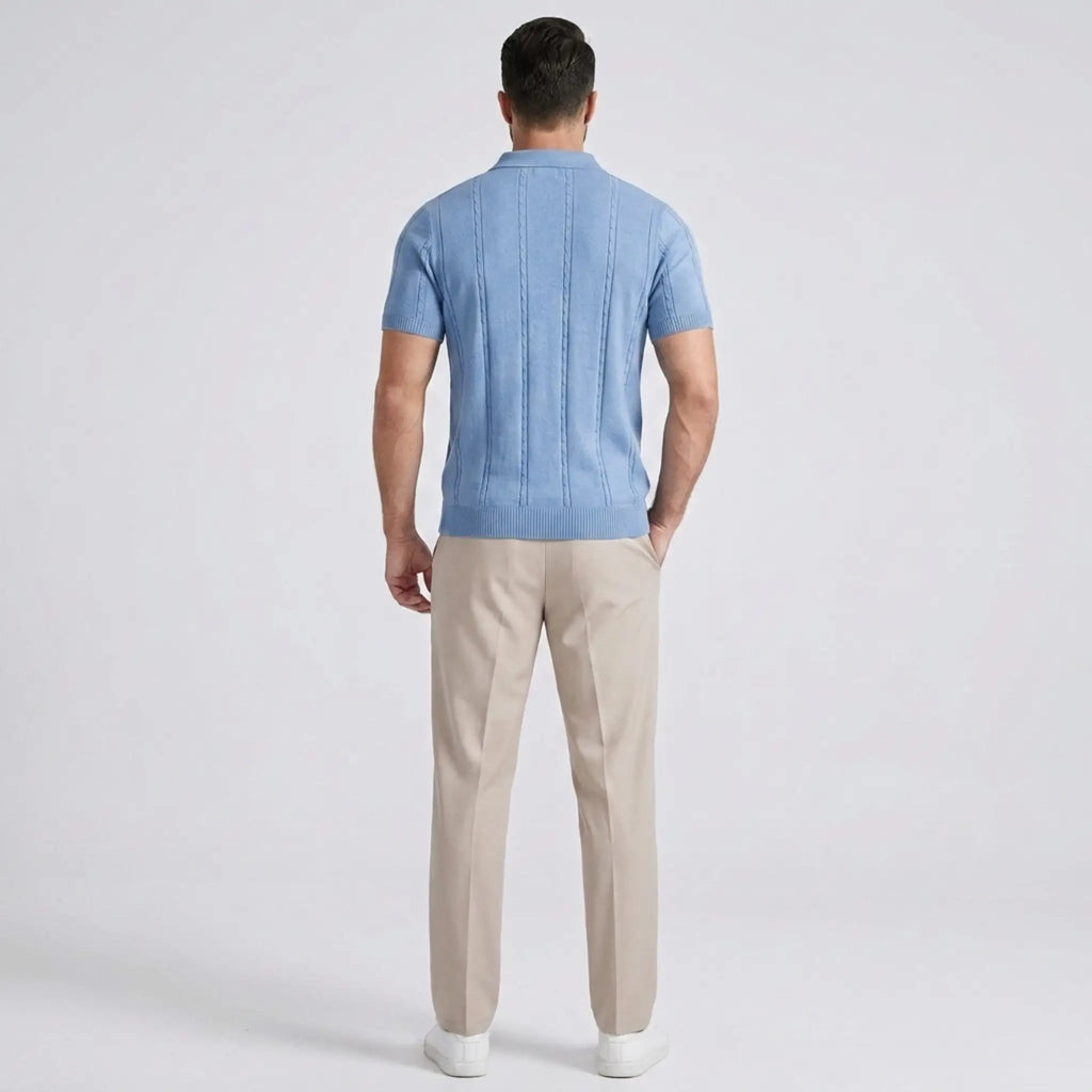 Back view of a man wearing a light blue short-sleeve knit polo shirt with beige trousers.