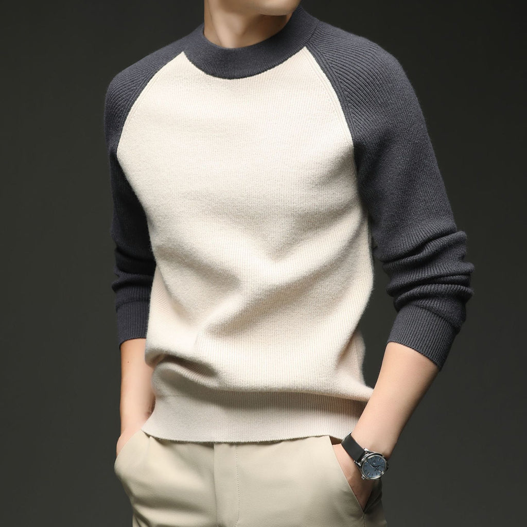 Man wearing beige and charcoal colorblock raglan knit sweater, close-up torso view with hand on hip