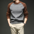 Man wearing grey and brown colorblock raglan knit sweater with hands in pockets, large front view