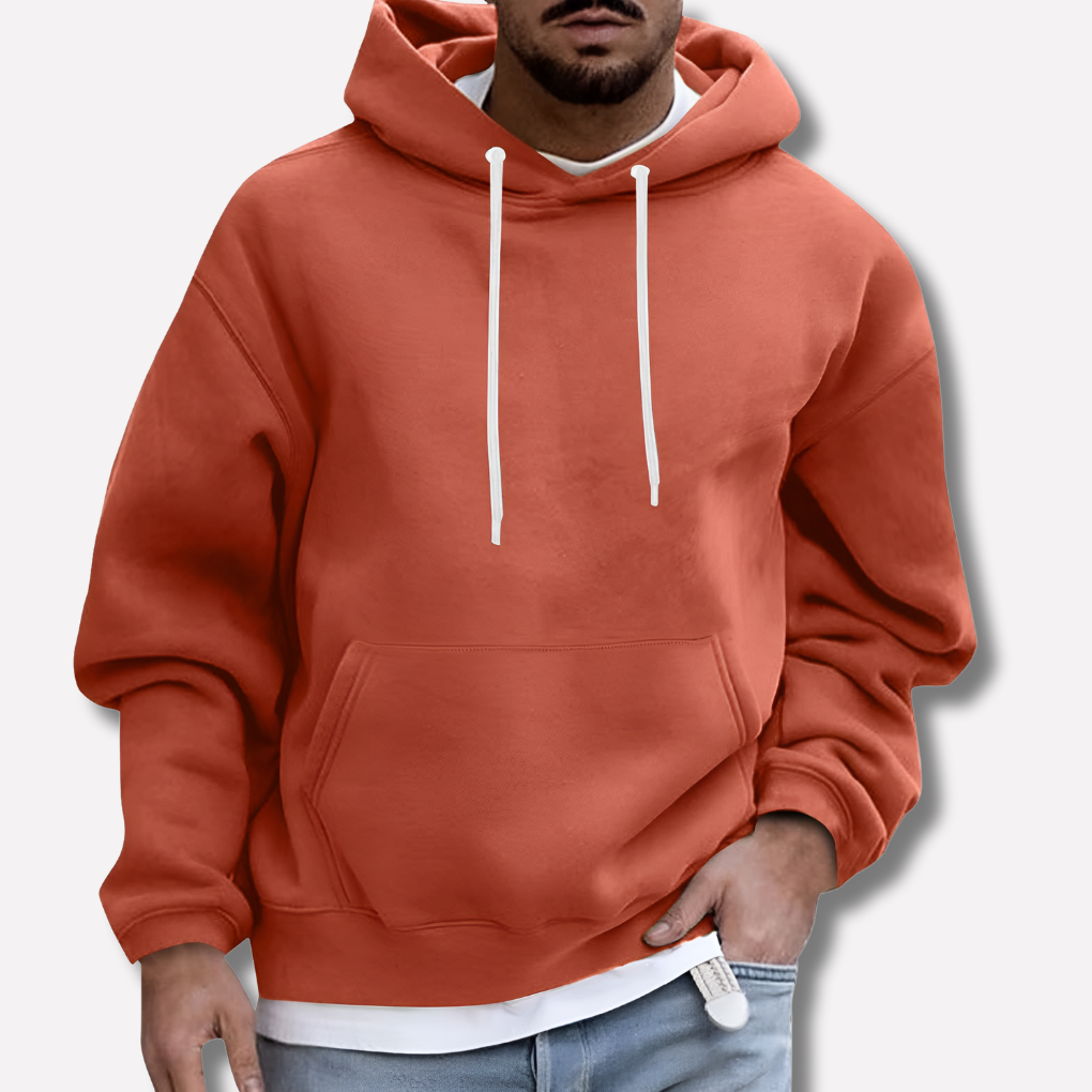 Orange pullover hoodie on model, close-up front view with hand in pocket