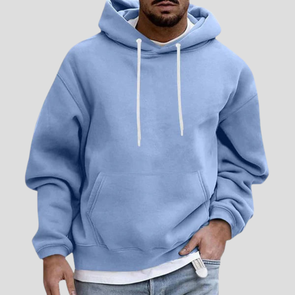 Man wearing light blue pullover hoodie and jeans with hand in pocket, close-up front view