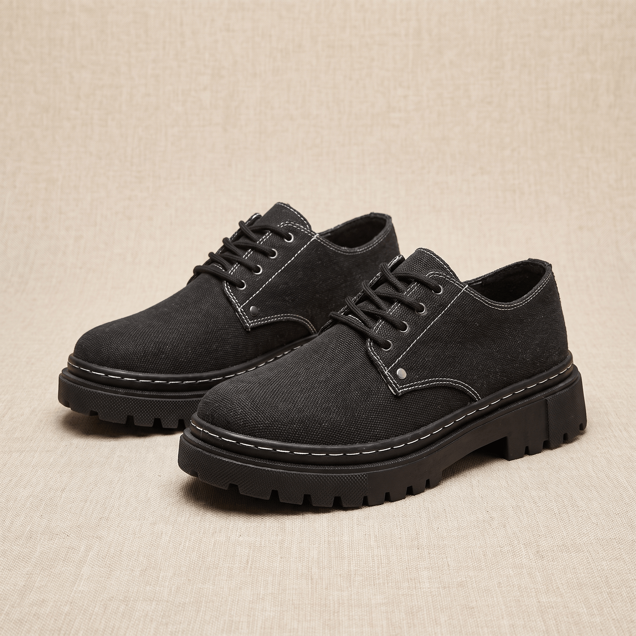 Pair of black denim Manuel lace-up shoes with white contrast stitching on beige backdrop