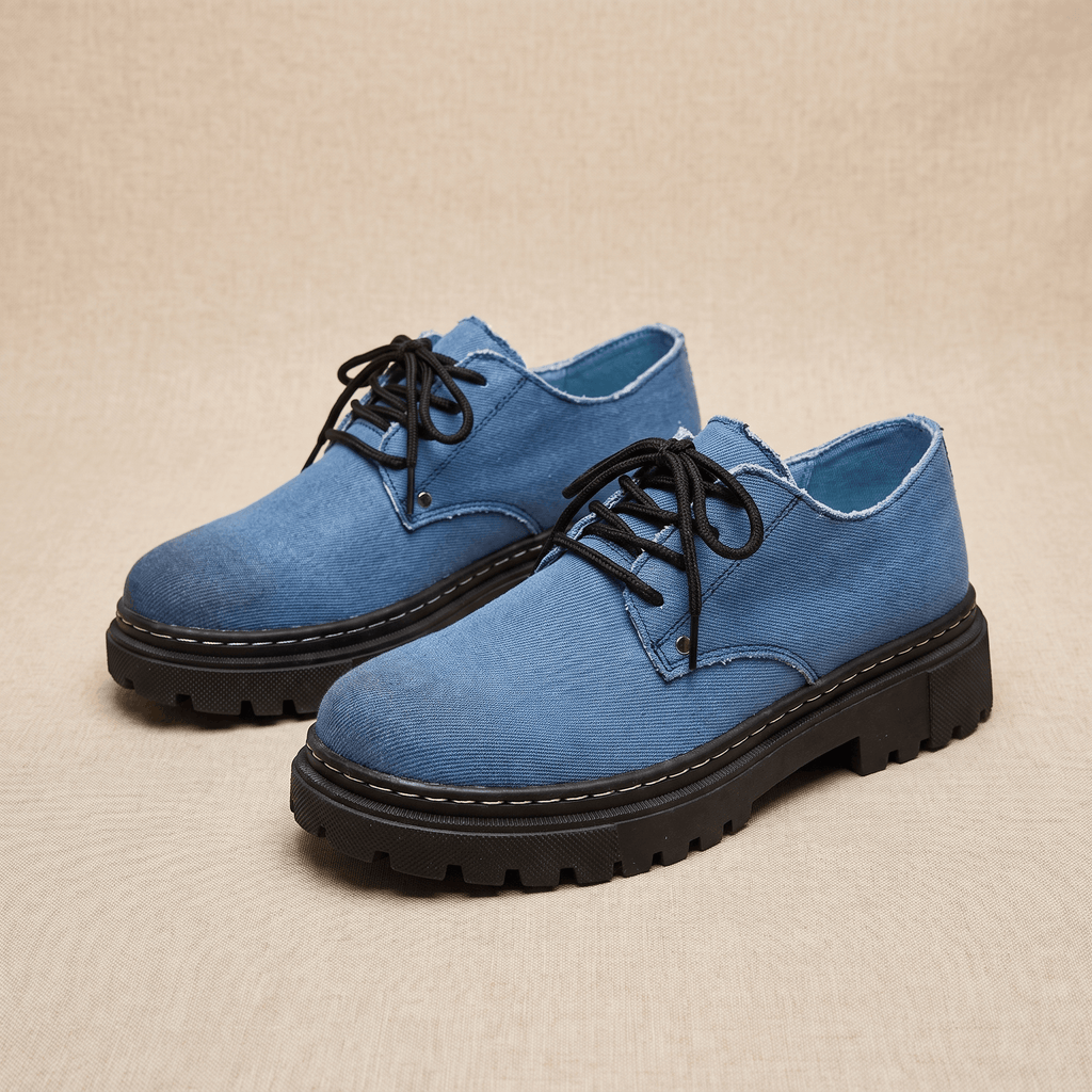 Pair of blue denim Manuel lace-up shoes with black rubber lug soles on beige backdrop