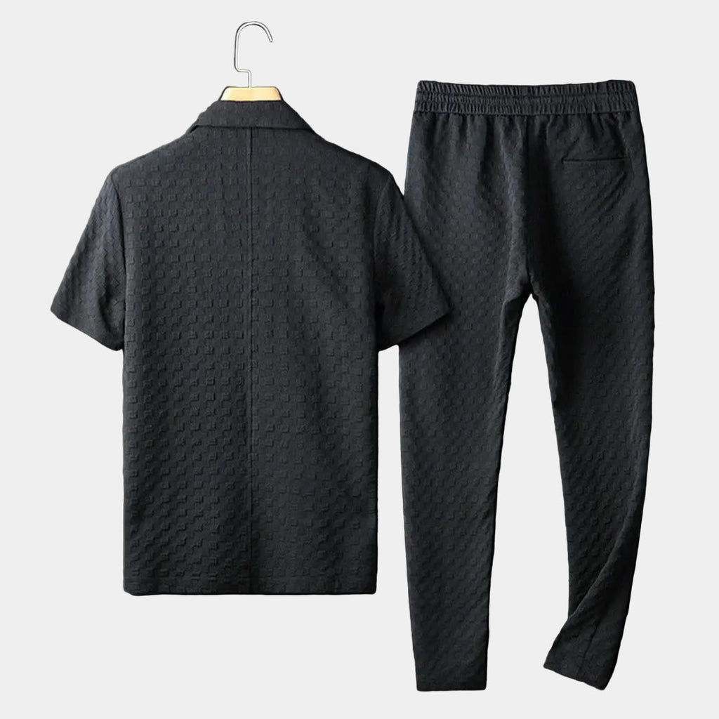 Back view of a men's black short-sleeve textured lounge shirt paired with matching drawstring pants.