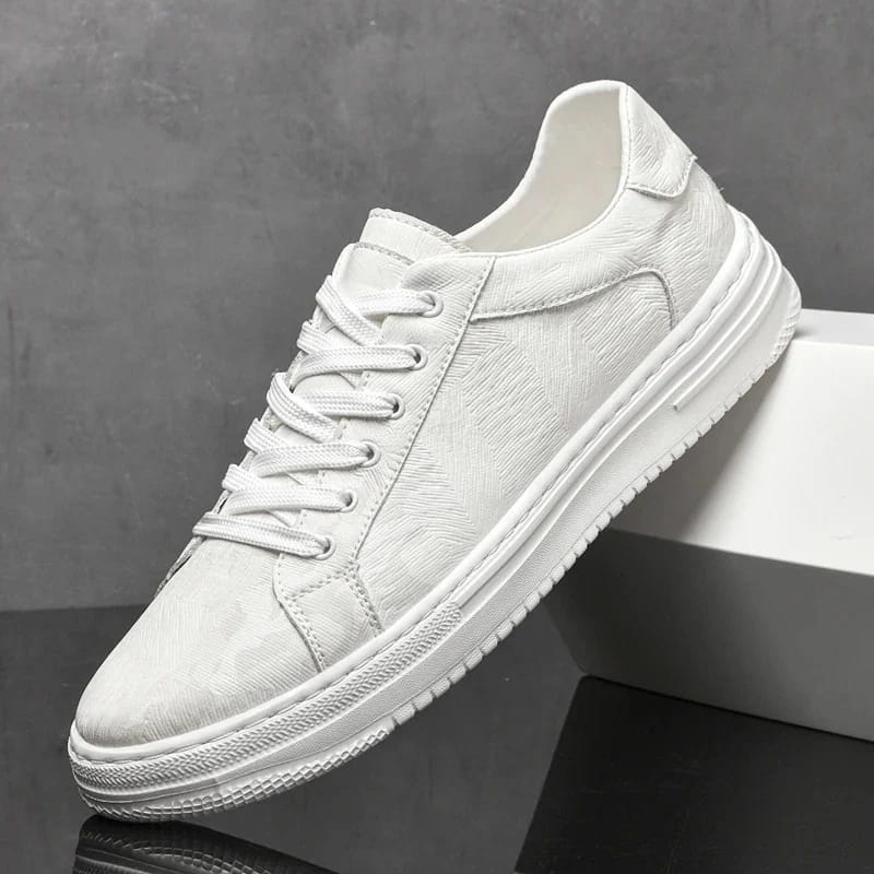 White leather sneaker with textured finish propped diagonally against a white block on a gray background