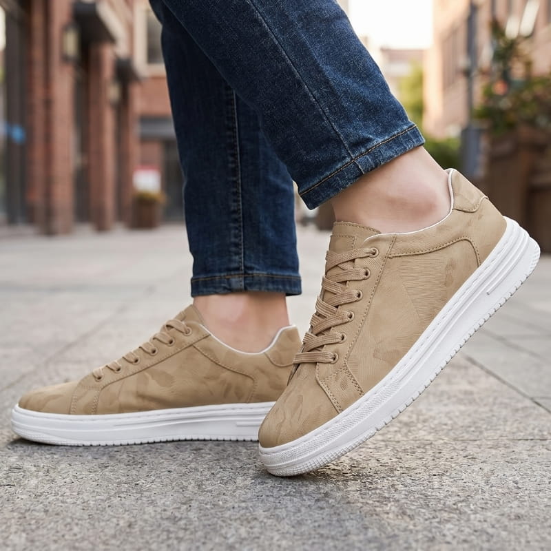Person wearing beige leather sneakers with jeans, walking on a cobblestone street