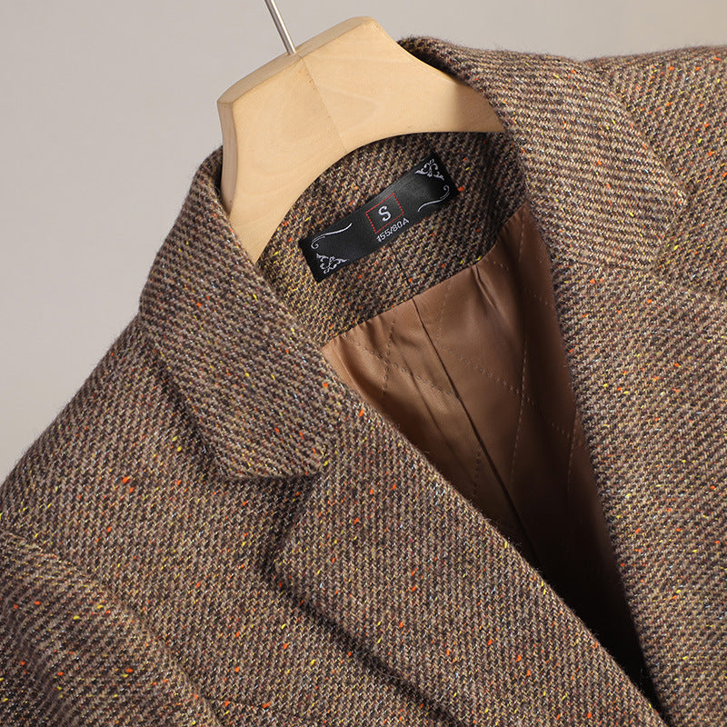 Close-up of the brown tweed blazer showing the notched lapel, textured fabric, and inner lining.