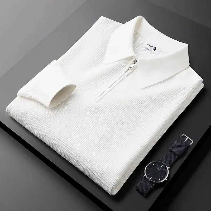 White textured half-zip polo sweater with a ribbed collar and long sleeves, folded on a dark surface.