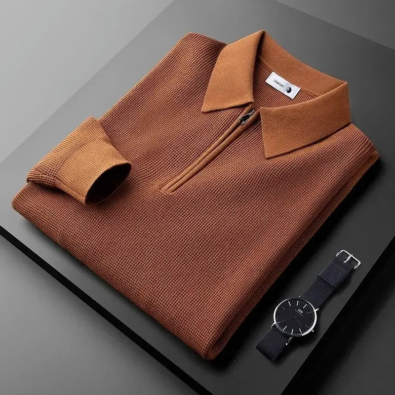 Brown textured half-zip polo sweater with a ribbed collar and long sleeves, neatly folded beside a wristwatch on a dark surface.