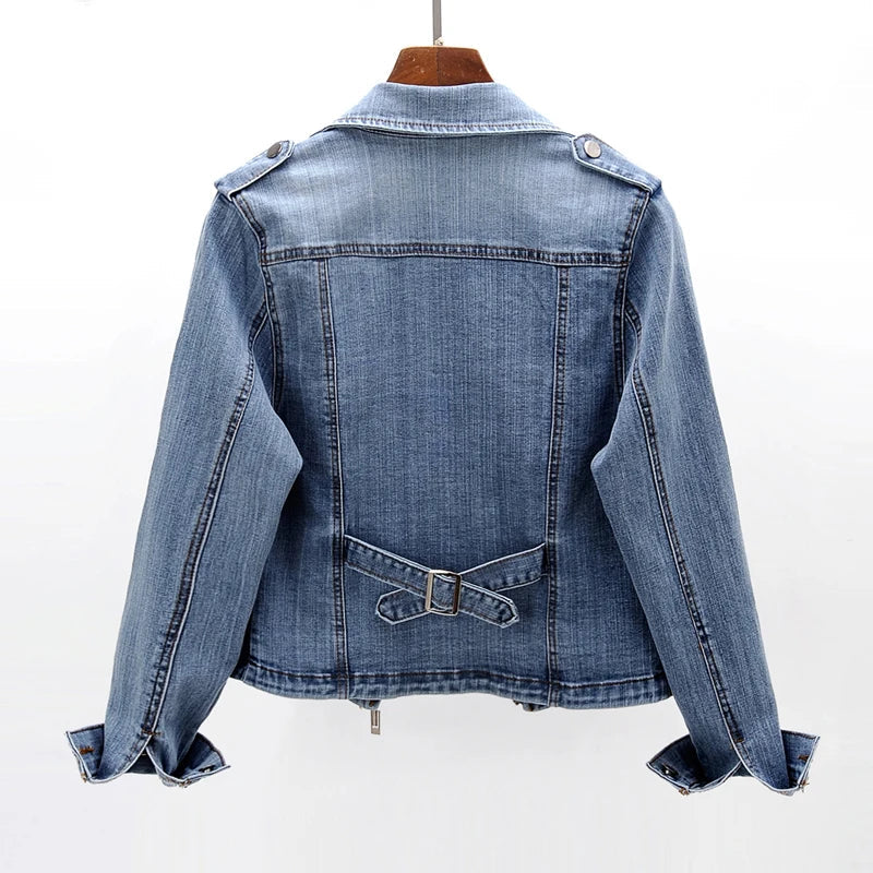 Back view of a women's blue denim moto jacket with a classic cropped fit, faded wash, and structured seams.