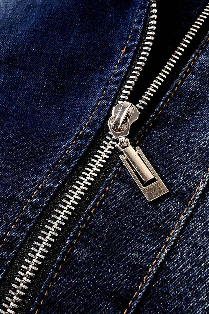 Close-up of the metal zipper and dark blue denim fabric on a women's moto jacket.