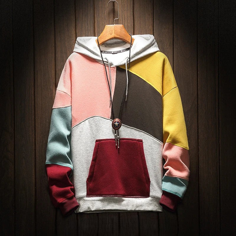 Colorblock hooded sweatshirt with kangaroo pocket on wooden hanger, close-up front view against dark wood background