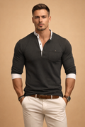 Man wearing a black long-sleeve polo sweater with a contrast white collar, button placket, ribbed cuffs, and a modern slim fit.